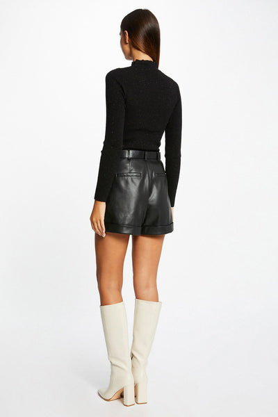 Black ribbed turtleneck sweater with subtle shimmer, back view, paired with black leather shorts and cream knee-high boots