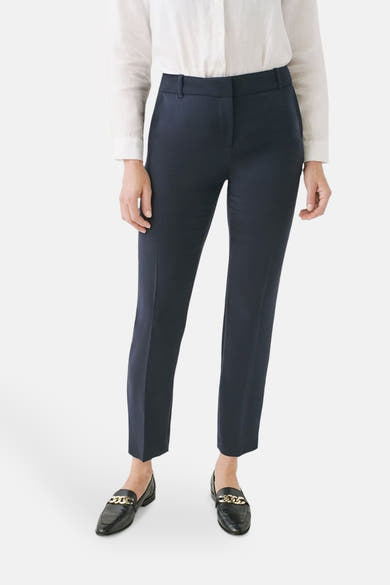 Pantalon de costume bleu de CAROLL, porté avec une chemise blanche et des mocassins noirs à chaîne dorée.
