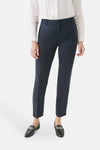 Pantalon de costume bleu de CAROLL, porté avec une chemise blanche et des mocassins noirs à chaîne dorée.

