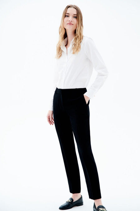 Pantalon de costume noir de CAROLL, porté avec une chemise blanche et des mocassins noirs.
