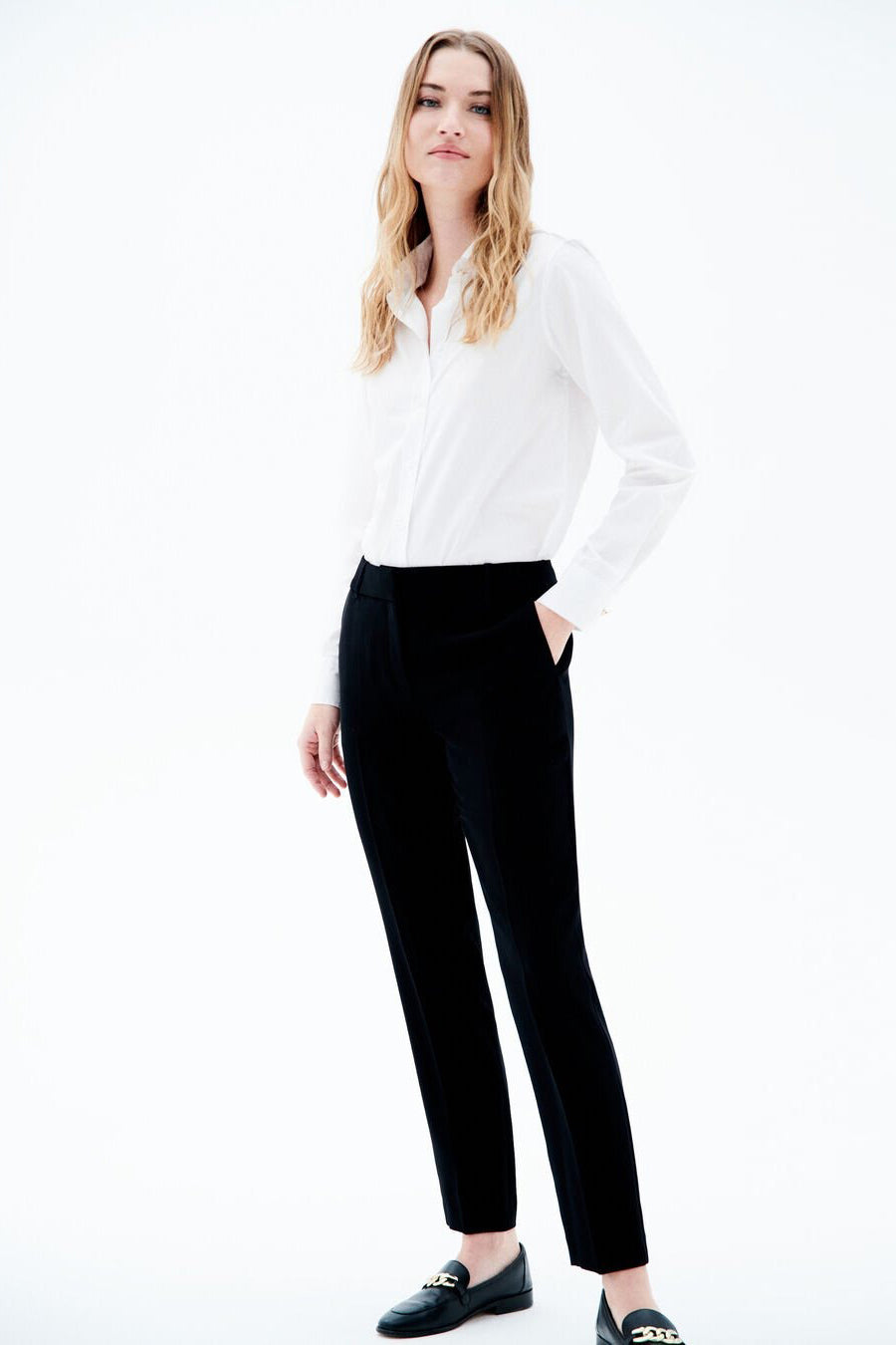 Pantalon de costume noir de CAROLL, porté avec une chemise blanche et des mocassins noirs.
