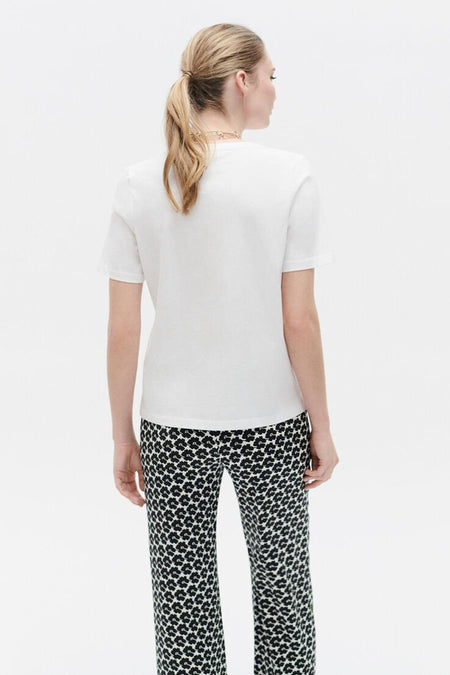 Wit T-shirt met korte mouwen van CAROLL, gedragen met een zwart-wit bloemenbroek.