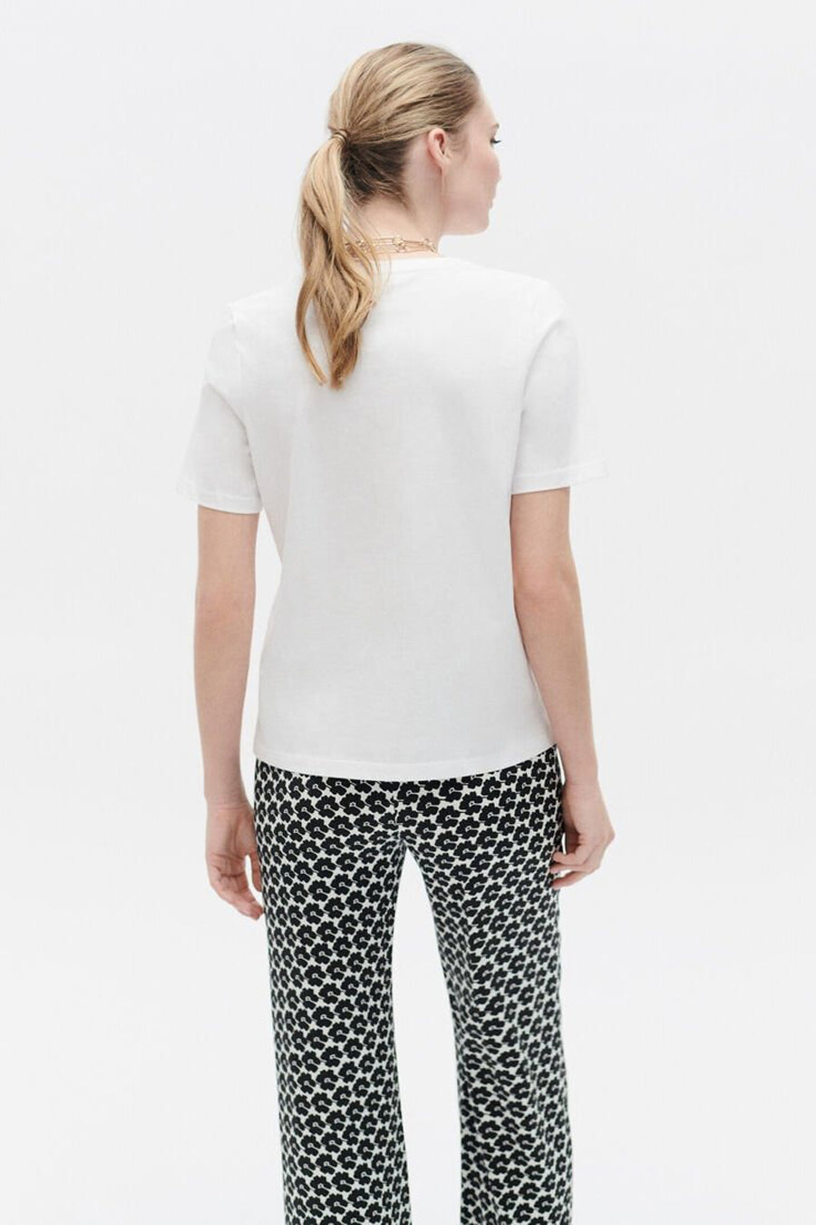 Wit T-shirt met korte mouwen van CAROLL, gedragen met een zwart-wit bloemenbroek.