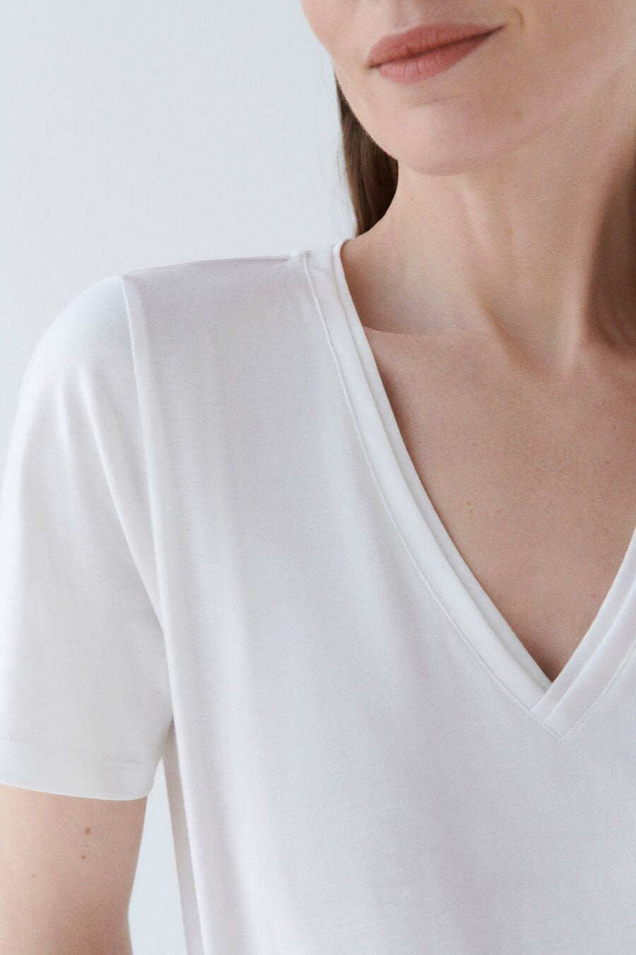 T-shirt blanc à manches courtes de CAROLL, coupe en V, porté par un modèle.