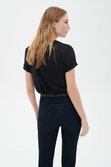 Zwart T-shirt met korte mouwen van CAROLL, gedragen met een jeans met hoge taille en een dunne riem.
