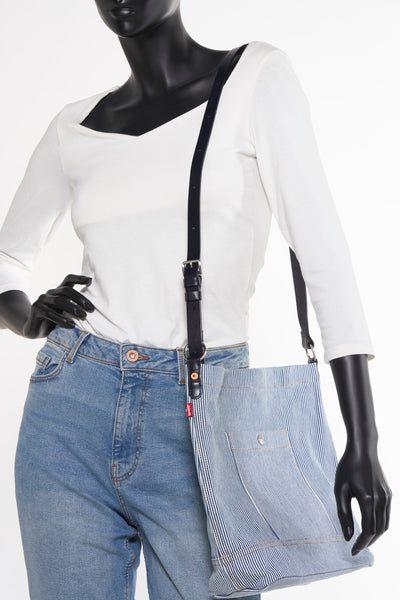 Gestreept blauw handtasje van Levi's Accessories, gedragen door een model met een spijkerbroek en een wit T-shirt.