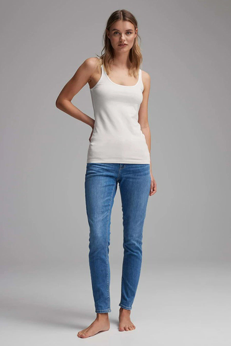 Débardeur blanc de OPUS porté avec un jean, manches et jambes nues.