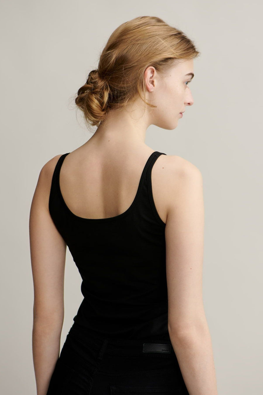 Débardeur noir OPUS, porté par une femme aux cheveux blonds relevés en chignon, vue de dos.