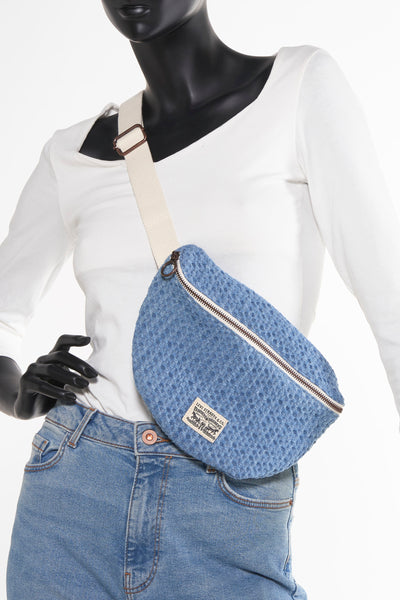 Sac à main bleu de Levi's Accessories, porté sur un mannequin vêtu d'un t-shirt blanc et d'un jean bleu.

