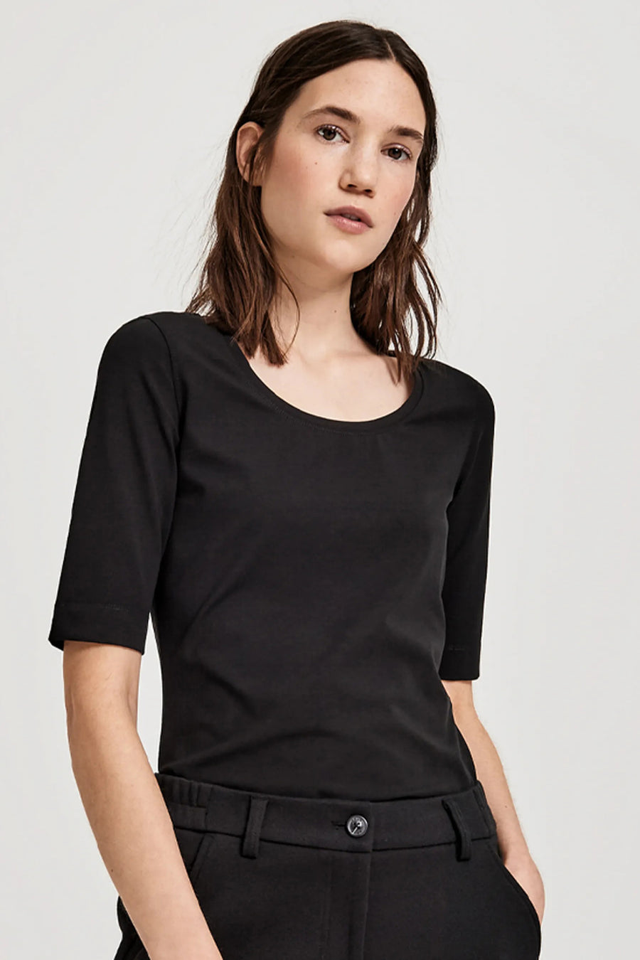 Top uni manches courtes noir d'OPUS, porté avec un pantalon noir assorti.