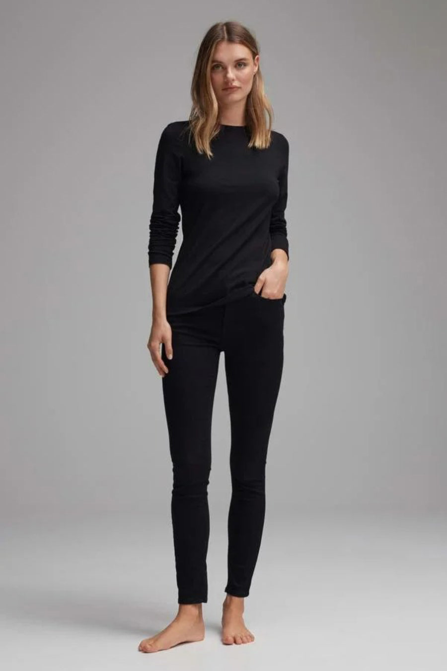 T-shirt noir à manches longues de OPUS, porté avec un pantalon noir, sur fond gris uni.