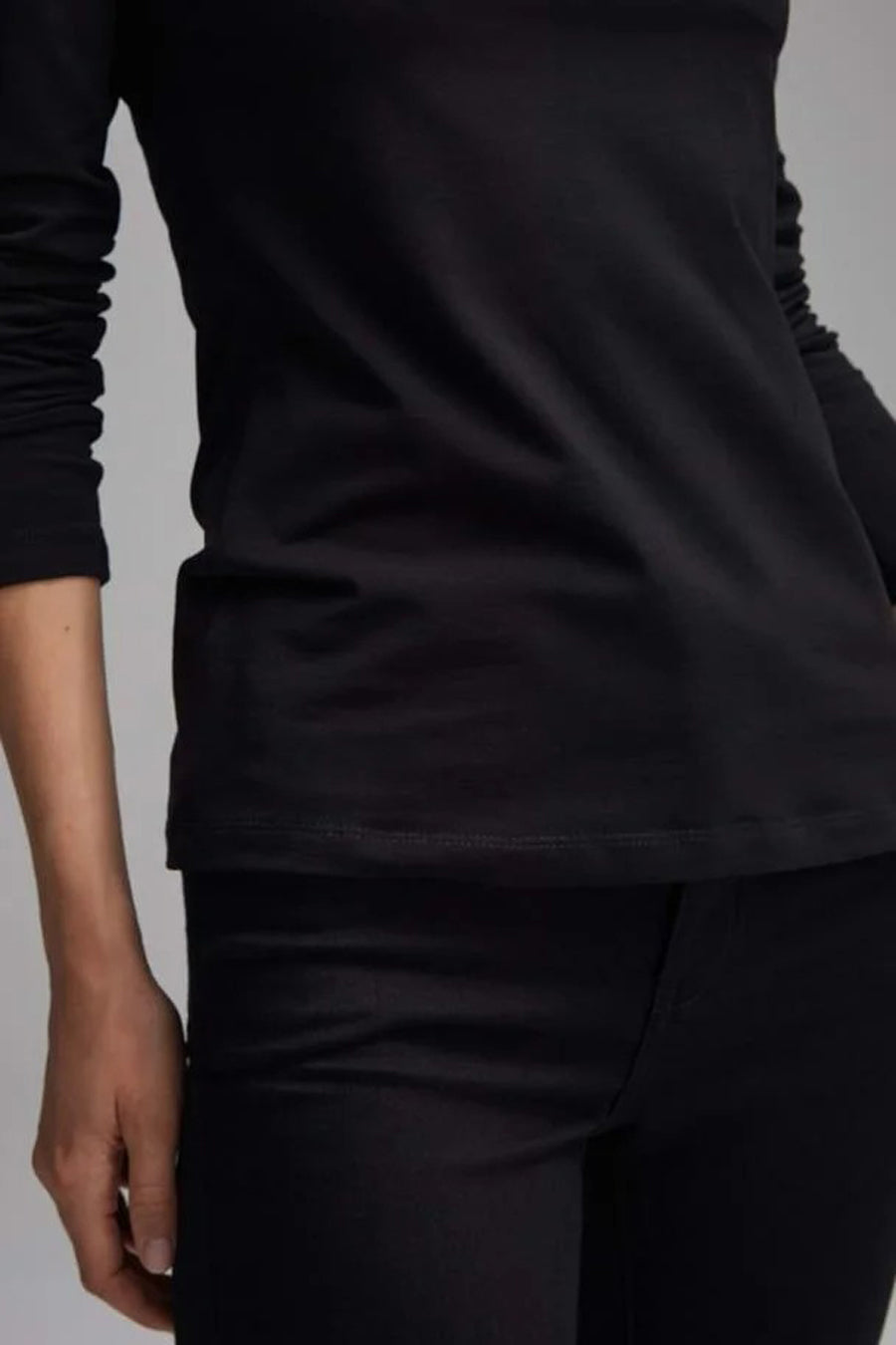 T-shirt à manches longues noir d'OPUS, porté avec un pantalon noir, sur fond gris clair.