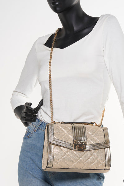 Sac à bandoulière doré de Morgan de Toi avec chaîne dorée, porté sur un mannequin en jean et pull blanc.