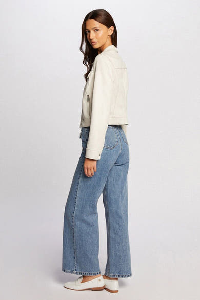 Veste courte beige de Morgan de Toi, avec fermeture éclair et poches, portée avec un jean ample et des mocassins blancs.