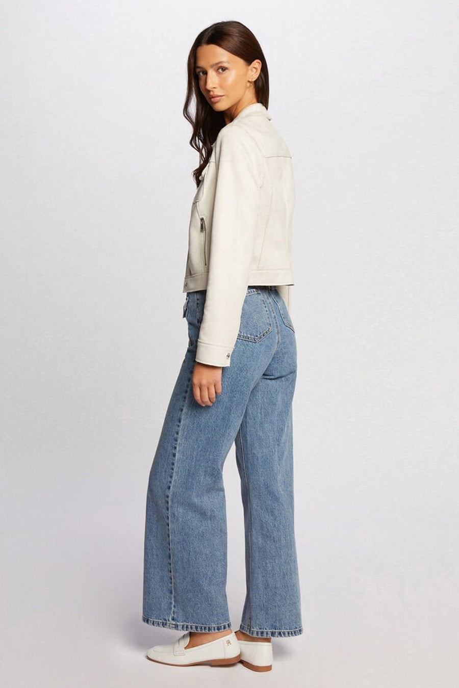 Veste courte beige de Morgan de Toi, avec fermeture éclair et poches, portée avec un jean ample et des mocassins blancs.