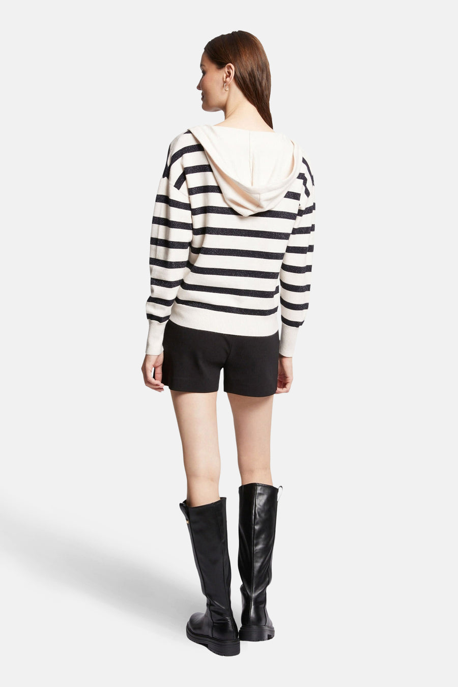 Pull à capuche blanc de Morgan de Toi, à rayures noires, porté avec un short noir et des bottes noires hautes.
