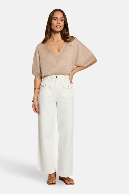 T-shirt beige à manches courtes de Morgan de Toi, avec un décolleté en V, porté avec un pantalon blanc.