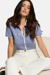 Blauwe cardigan van Morgan de Toi met gouden knopen, gedragen met een witte jeans.