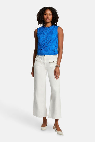 Blauwe mouwloze blouse van Morgan de Toi in kant, gedragen met een witte broek.