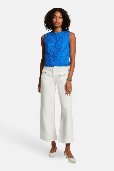 Blauwe mouwloze blouse van Morgan de Toi in kant, gedragen met een witte broek.