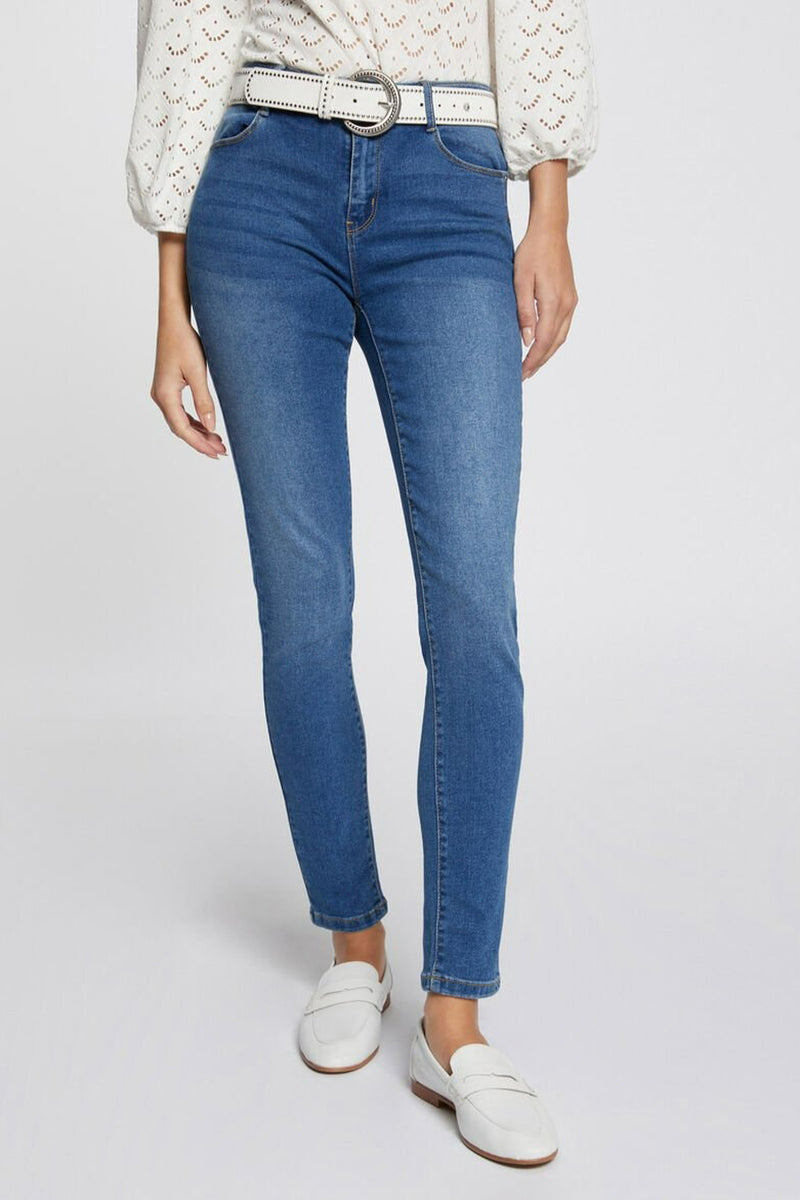Jeans slim bleu moyen de Morgan de Toi, portés avec une ceinture blanche et des chaussures plates blanches.
