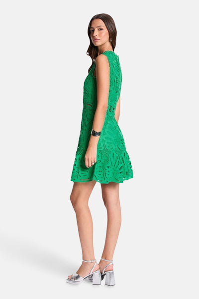 Robe courte verte en dentelle de Morgan de Toi, avec une coupe évasée et des chaussures argentées à talons.

