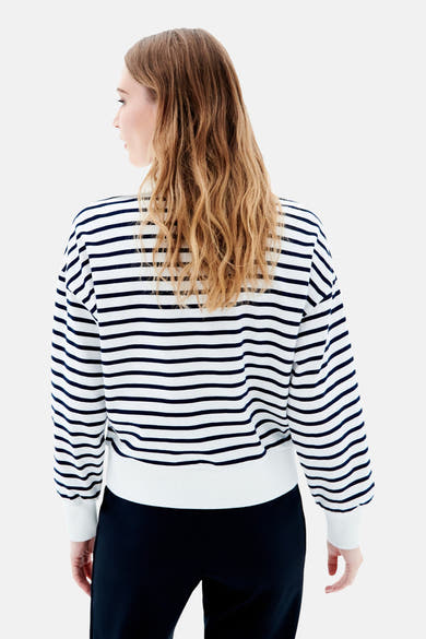 Blauwe V-hals trui van CAROLL, marineblauwe en witte horizontale strepen, gedragen met een zwarte broek.