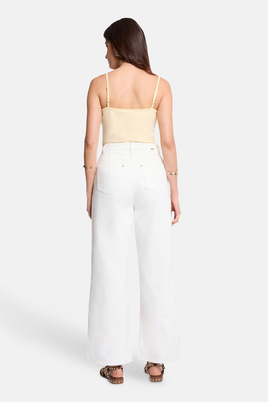 Gele top met dunne bandjes van Morgan de Toi, gedragen met een witte high-waisted jeans en sandalen met studs. Achterzicht.