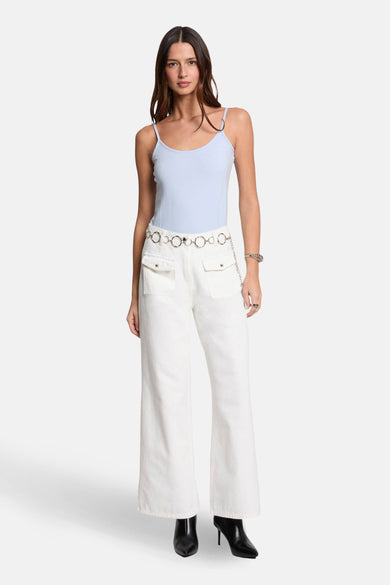 Top bleu à fines bretelles de Morgan de Toi, porté avec un pantalon blanc taille haute et une ceinture chaîne.