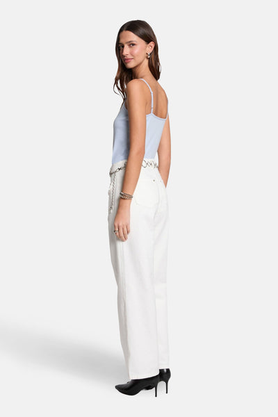 Top à fines bretelles bleu, de Morgan de Toi, porté avec une ceinture à chaînes et un pantalon blanc.