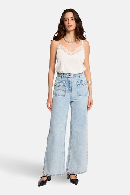 Top à fines bretelles blanc de Morgan de Toi, avec dentelle, porté avec un jean et des chaussures noirs.
