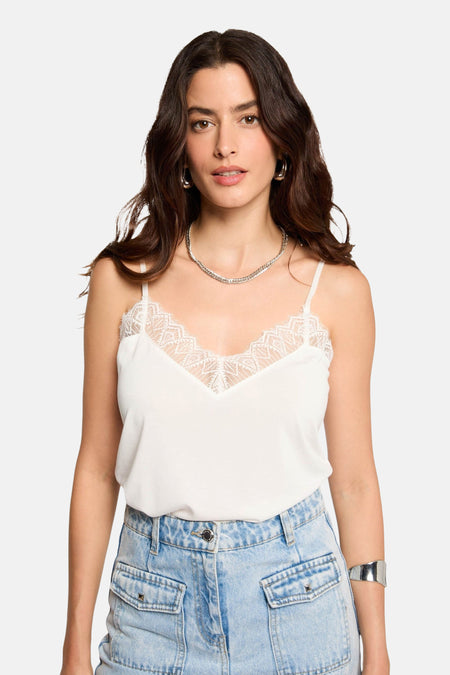 Top blanc à fines bretelles de Morgan de Toi, orné de dentelle sur l'encolure en V, porté avec un jean taille haute.