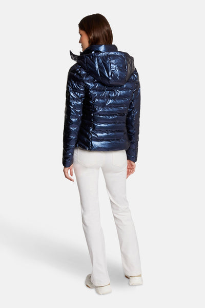 Korte, glanzende blauwe jas van Morgan de Toi, met capuchon en gedragen met een witte broek.