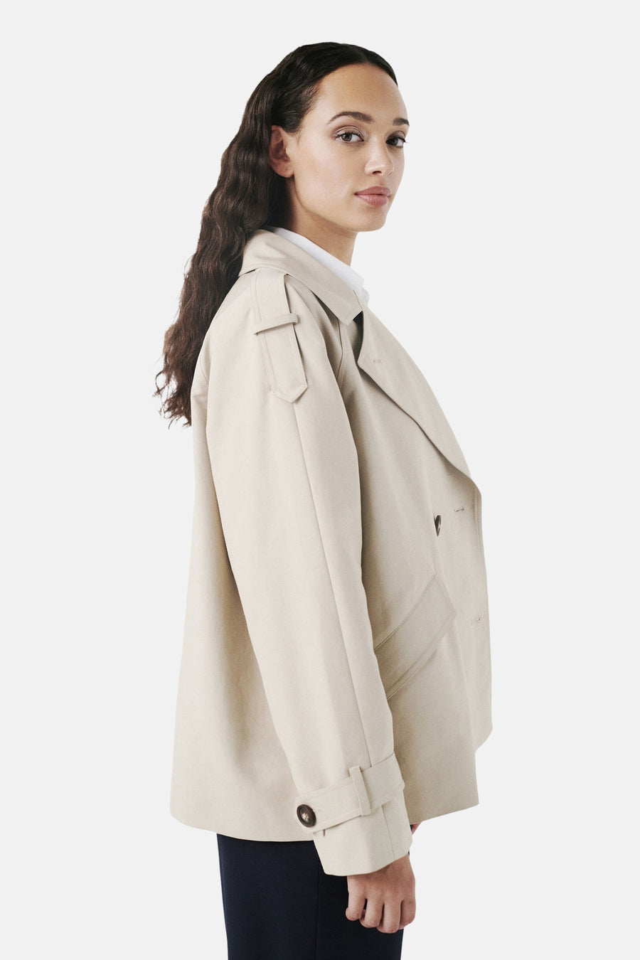 Veste courte beige de CAROLL, avec revers et poches plaquées, portée sur un haut blanc et un pantalon marine.