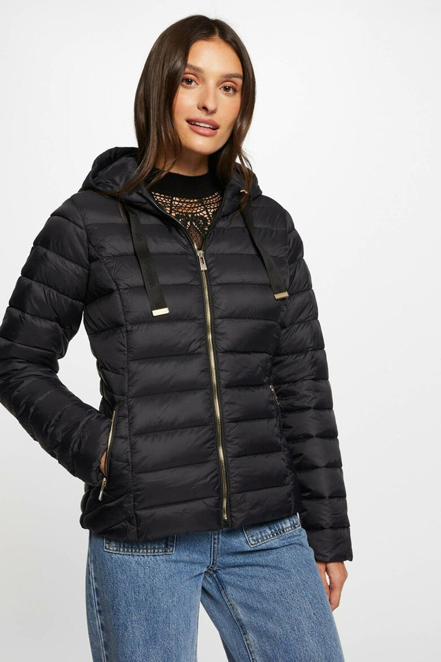 Veste courte noire de Morgan de Toi avec capuche et fermeture éclair dorée, portée sur un pull en dentelle.