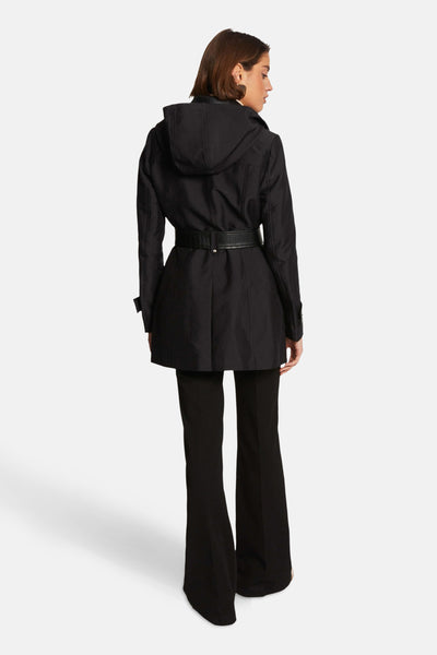 Veste noire de Morgan de Toi avec ceinture, capuche et coupe évasée portée avec un pantalon noir.