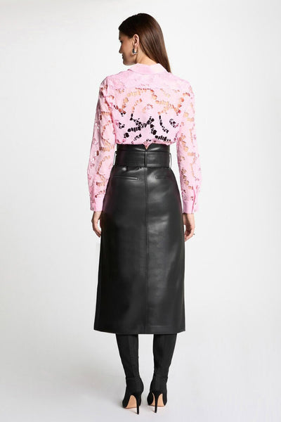 Jupe longue noire en cuir de Morgan de Toi, coupe droite, portée avec un chemisier rose ajouré et des bottines noires à talons aiguilles.