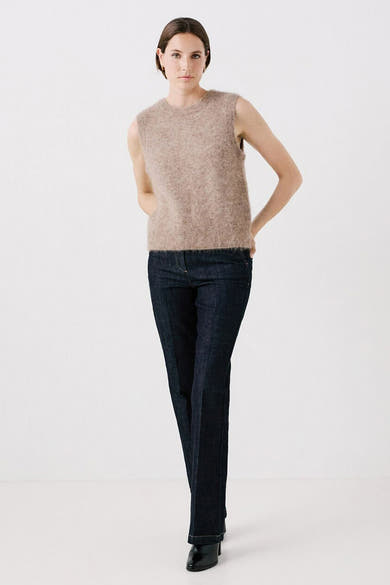 Débardeur beige en mohair de CAROLL, porté avec un pantalon bleu foncé et des chaussures noires.

