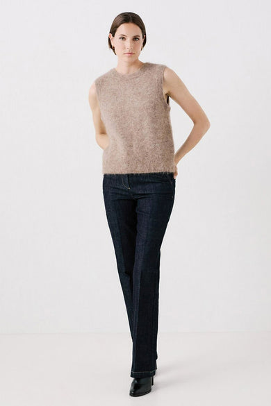 Débardeur beige en mohair de CAROLL, porté avec un pantalon bleu foncé et des chaussures noires.

