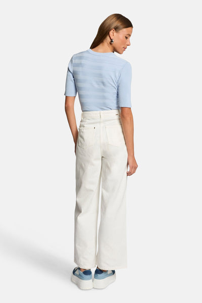 Ronde hals trui van Morgan de Toi in het blauw, toon-op-toon horizontale strepen, gedragen met een witte broek en sleehakken.