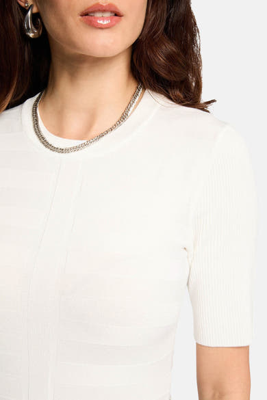 Witte rondehals-trui van Morgan de Toi, in een getextureerde breisel, gedragen met een zilveren ketting en oorbellen.