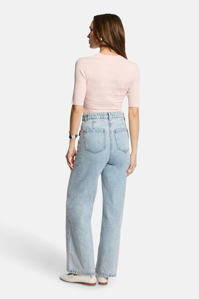 Roze rondehals trui van Morgan de Toi, gedragen met een lichtblauwe high-waist jeans en witte loafers.
