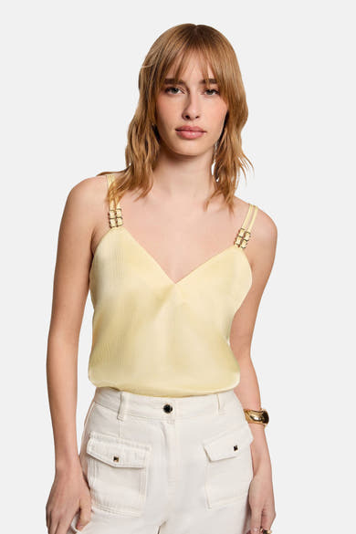Blouse jaune sans manches de Morgan de Toi, à texture subtile et bretelles décoratives, portée avec un pantalon blanc.
