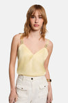 Blouse jaune sans manches de Morgan de Toi, à texture subtile et bretelles décoratives, portée avec un pantalon blanc.
