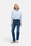 Jean bootcut bleu moyen de CAROLL, porté avec une chemise rayée et des sandales.
