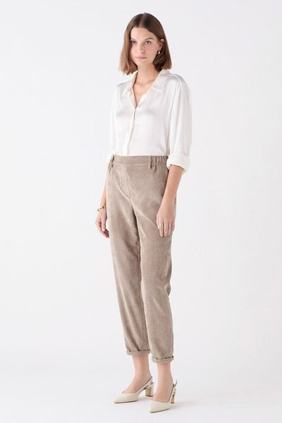 Chino beige de CAROLL, en velours côtelé, porté avec une chemise blanche et des escarpins clairs.
