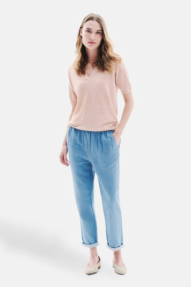 Pantalon 7/8 en denim bleu moyen de CAROLL, porté avec un t-shirt rose et des chaussures neutres.

