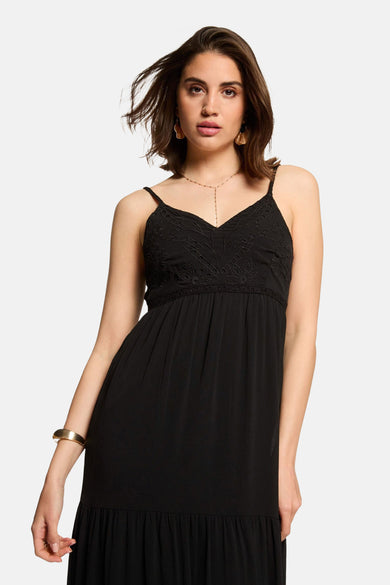 Robe noire fluide de Morgan de Toi avec bretelles fines, détails brodés et bijoux dorés.
