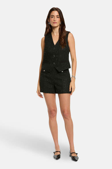 Short noir by Morgan de Toi, avec texture et boutons décoratifs, porté avec un veston assorti et des chaussures noires.