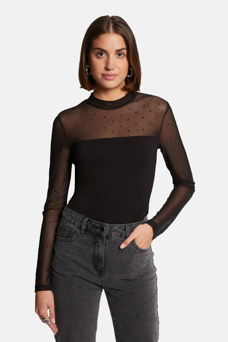 T-shirt noir à manches longues de Morgan de Toi, avec détails en tulle et strass, porté avec un jean gris délavé.

